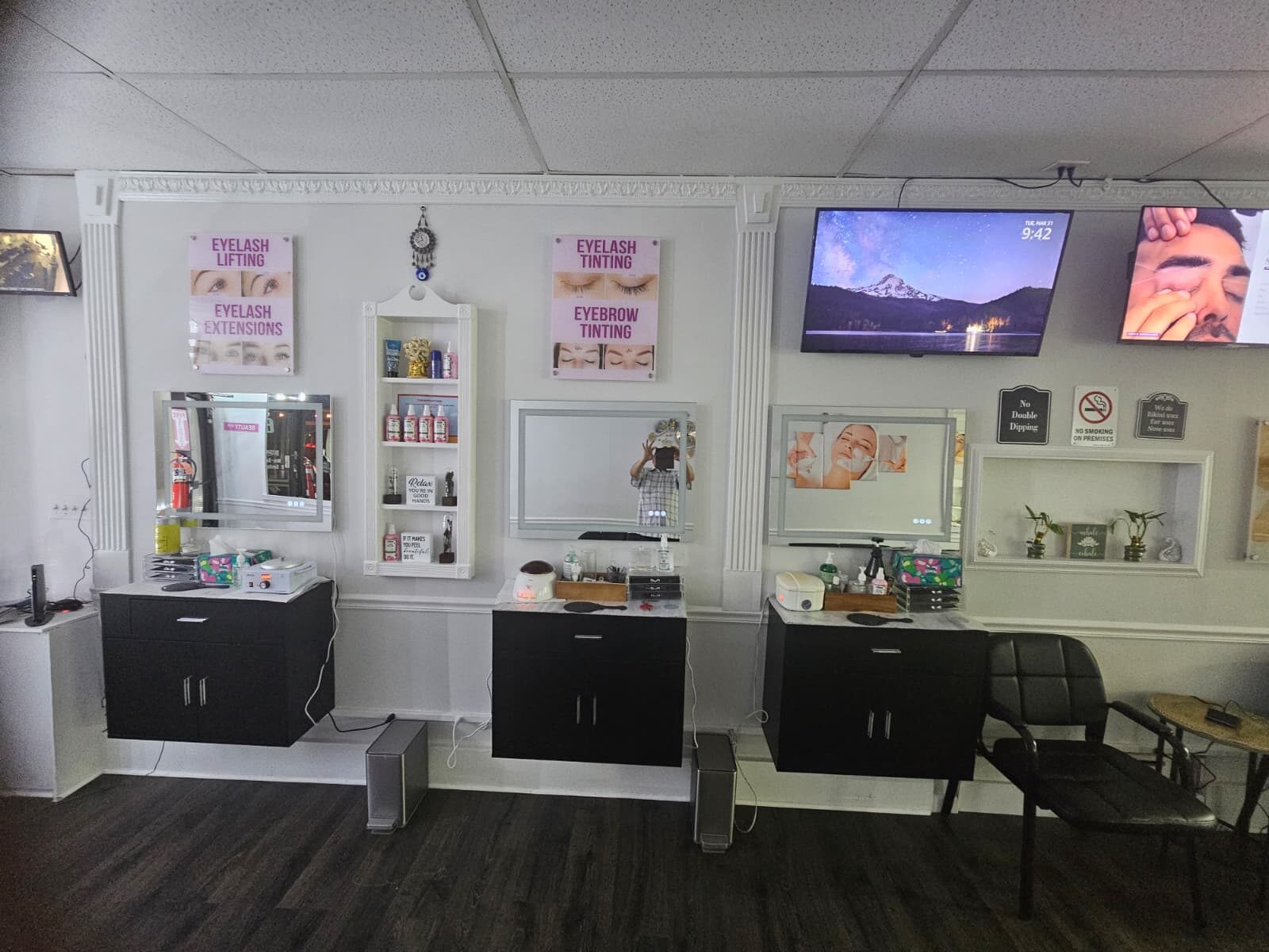A brow and lash station at Creative Brows — mirrors, product shelves, and eyebrow threading and tinting posters in the newly renovated Lynbrook studio